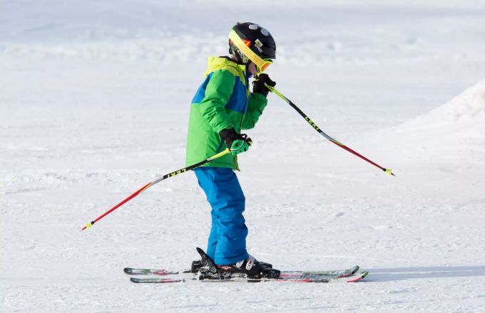 Früh übt sich: Dieser kleine Skifahrer sieht schon aus wie ein echter Profi. Kind Ski Schnee Seitenansicht