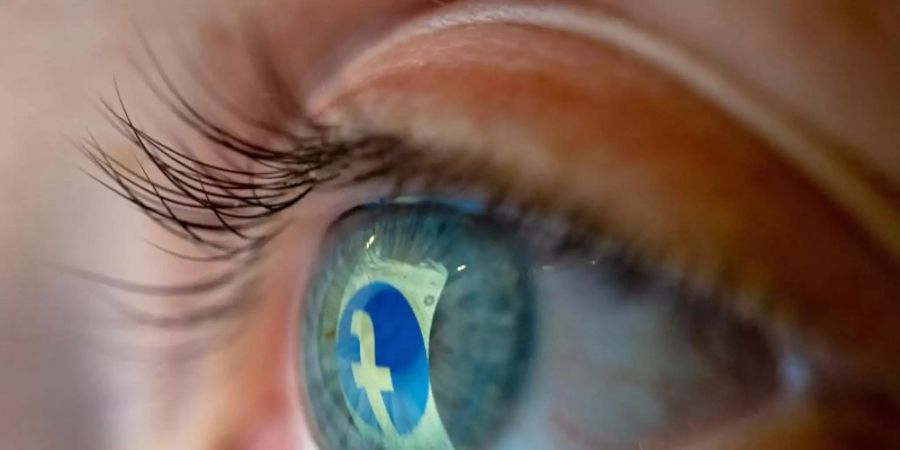 Das Facebook-Logo spiegelt sich in einem Auge. Foto: Mohssen Assanimoghaddam/dpa