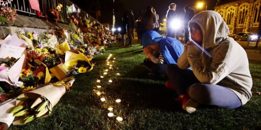 Menschen trauern in Christchurch vor Kerzen und Blumen, die in Gedenken an die Opfer der Anschläge niedergelegt wurden. Foto: kyodo