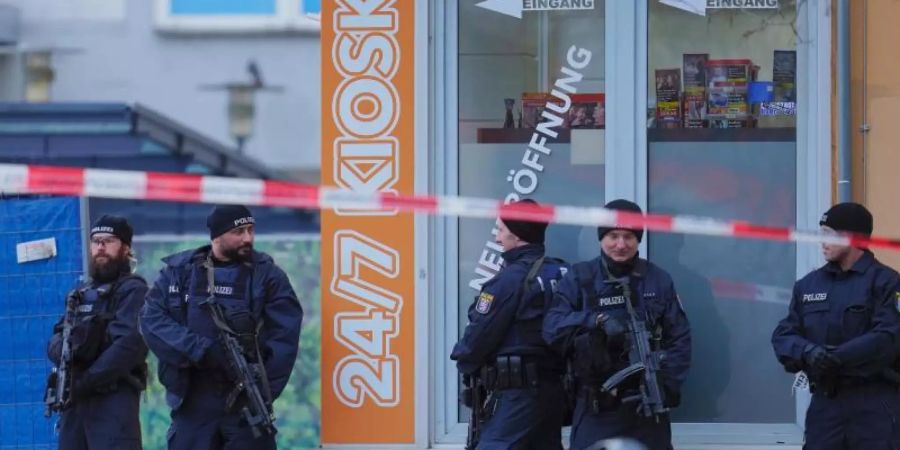 Mit Maschinenpistolen bewaffnete Einsatzkräfte der Polizei vor einem Kiosk am Tatort in Hanau-Kesselstadt. Foto: Uwe Anspach/dpa