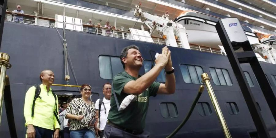 Nachdem sie das Kreuzfahrtschiff «Westerdam» im Hafen von Sihanoukville verlassen, zeigen sich einige Passagiere sichtbar erleichtert. Foto: Heng Sinith/AP/dpa