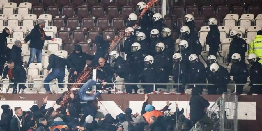 Polizeikräfte drängen randalierende Dresden-Fans zurück in den Gästeblock. Foto: Christian Charisius/dpa