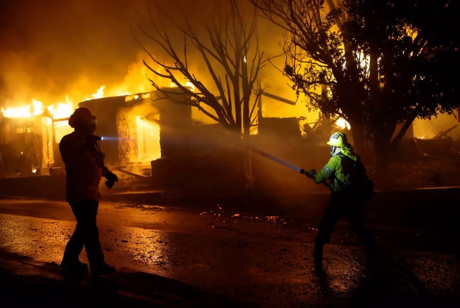 Feuerwehrleute versuchen, ein Haus vor einem Lauffeuer zu retten.