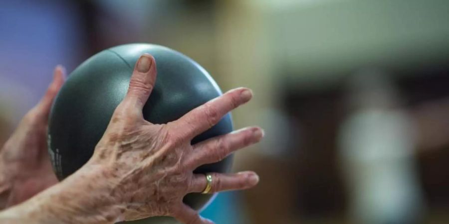 Eine Rentnerin macht in bei der Seniorengymnastik eine Übung mit dem Ball. Foto: Andreas Arnold/dpa