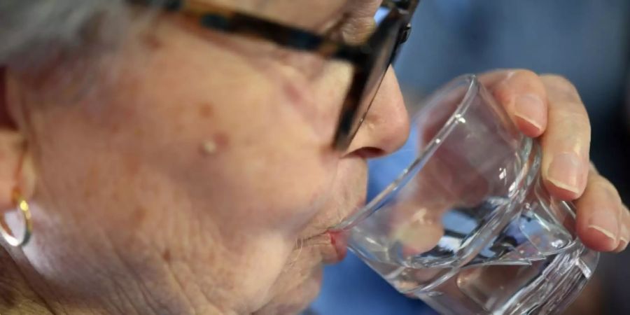 Bewohnerin von Altenheim trinkt Glas Wasser