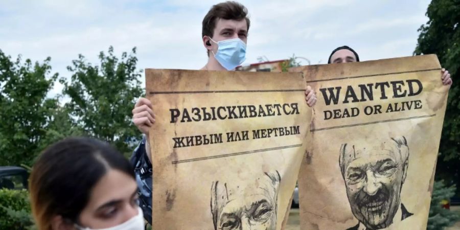 Demonstranten mit Plakaten mit Lukaschenkos Konterfei