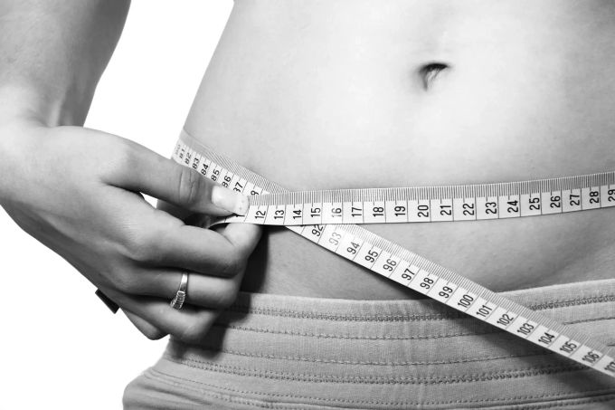 Eine Frau misst ihren Bauchumfang. Bauch