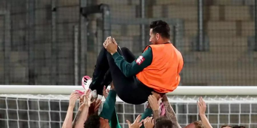 Claudio Pizarro von Werder Bremen wird nach Spielende von seinen Teamkollegen in die Luft geworfen. Foto: Tom Weller/dpa