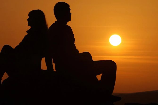 paar im sonnenuntergang, rücken an rücken