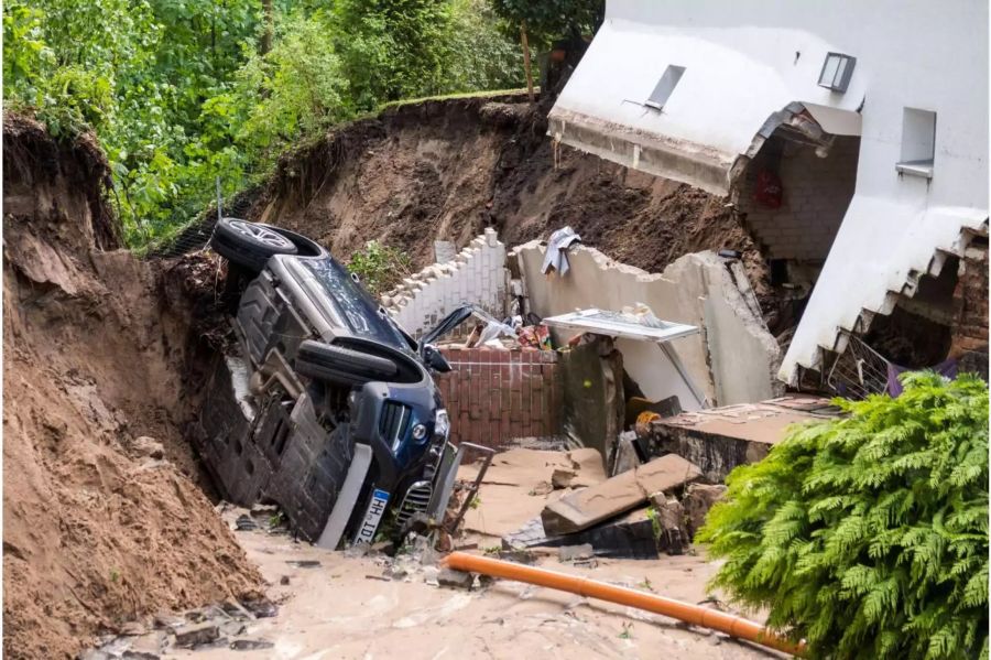 Ein Auto liegt im Hamburger Stadtteil Lohbrügge in einer Senke. Das anliegende Wohnhaus musste wegen der Unterspülung evakuiert werden.