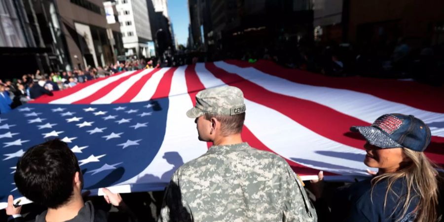 An der Parade zum Tag der Veteranen halten Besucher eine überdimensional grosse Fahne der USA in den Händen.