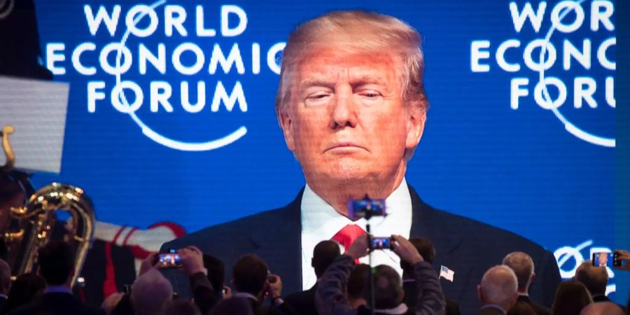 Teilnehmer schauen auf einem Bildschirm dem US-amerikanischen Präsidenten Donald Trump am 48. WEF in Davos GR zu.