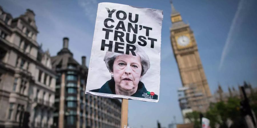 Ein Demonstrant hält ein Schild mit einem Abbild von Premierministerin May der Aufschrift «You can't trust her» auf einer Demonstration im Rahmen der Queen's speech in London.