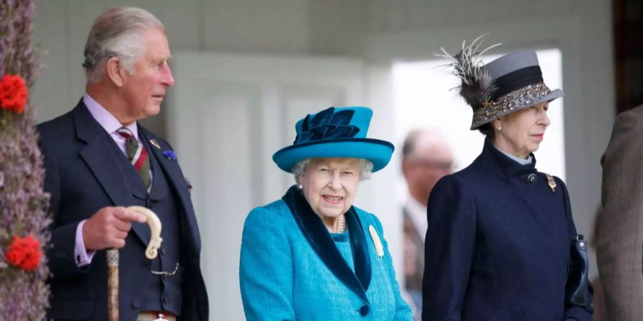 Queen Elizabeth II. (M) steht beim Braemar Gathering zwischen ihrem Sohn und Thronfolger Prinz Charles (l) und Prinzessin Anne (r).