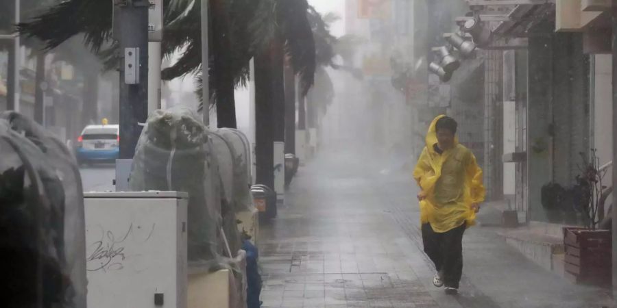 Ein Mensch geht in Japan bei starkem Regen und Wind über eine Strasse.