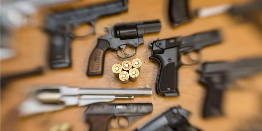 Pistolen, Revolver und Munition liegen auf einem Tisch