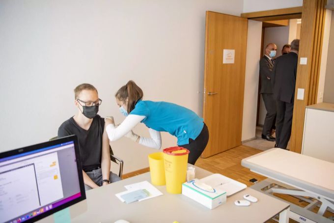 Ein Mann wird in der Bristenpraxis in Altdorf UR gegen das Coronavirus geimpft, mit Bundesrat Alain Berset im Hintergrund, anlässlich seines Besuchs im Kanton. Impfung Coronavirus Uri Berset