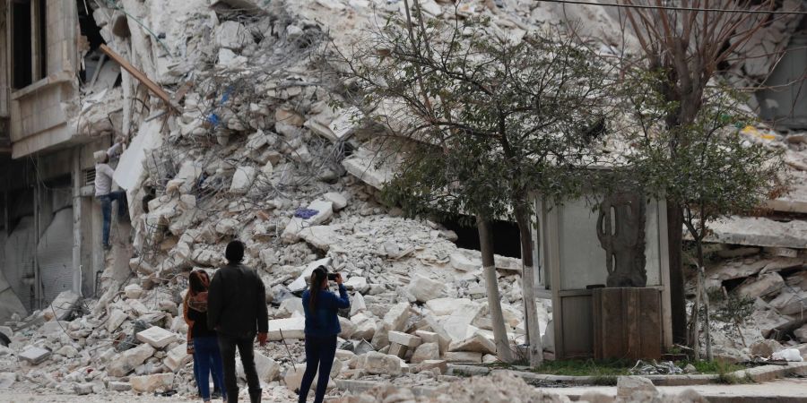 Menschen stehen vor den Trümmern eines Gebäudes, das bei dem jüngsten Erdbeben in Aleppo zerstört wurde.