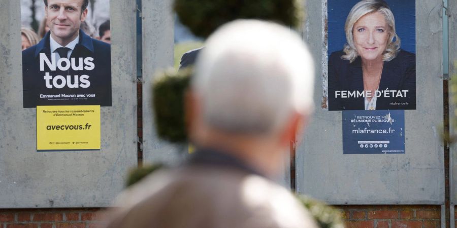 Ein Mann geht an Wahlkampfplakaten für die Präsidentschaftswahl in Frankreich vorbei.
