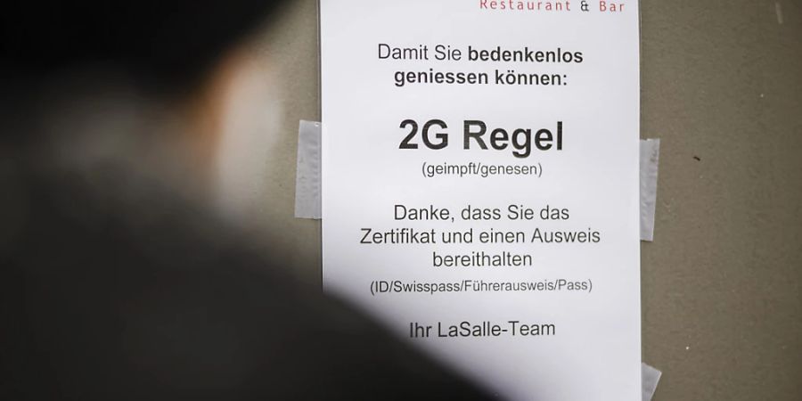 Die Umsatzeinbussen wegen Omikron halten sich bisher in Grenzen: Eine Person liest die 2G-Regel bei einem Restaurant (Archivbild).