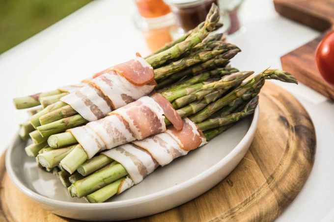 Herzhaft geräucherter Schinken – etwa aus dem Schwarzwald – verträgt sich gut mit grünem Spargel. Spargel grün Holzbrett Schinken