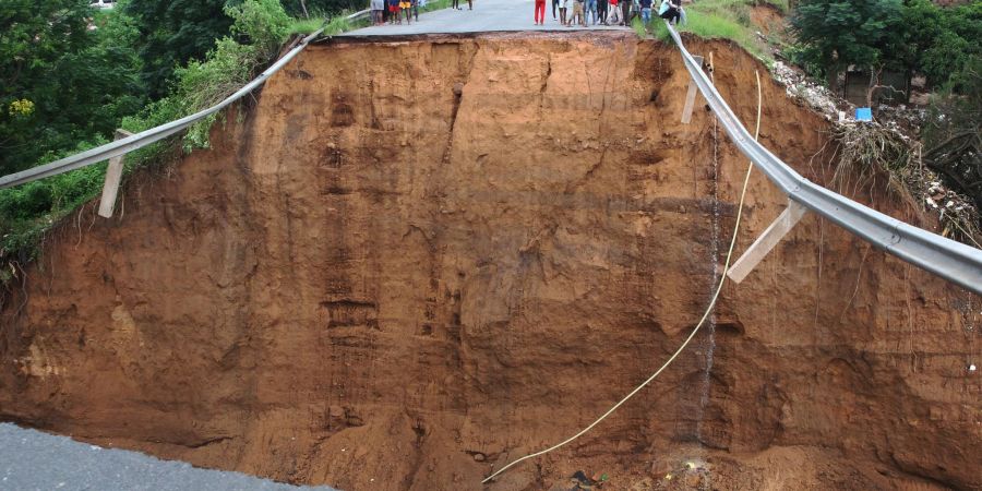 Gestrandete Menschen stehen nach ungewöhnlich heftigen Niederschlägen vor einer weggeschwemmten Brücke in Durban.