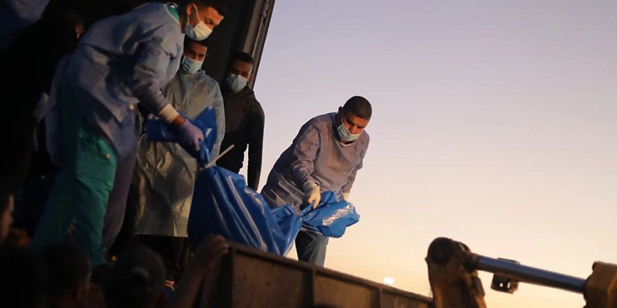 Sanitäter laden die Leichen von palästinensischen Opfern, die im Norden des Gazastreifens getötet wurden, in ein Massengrab. Foto: Mohammed Talatene/dpa