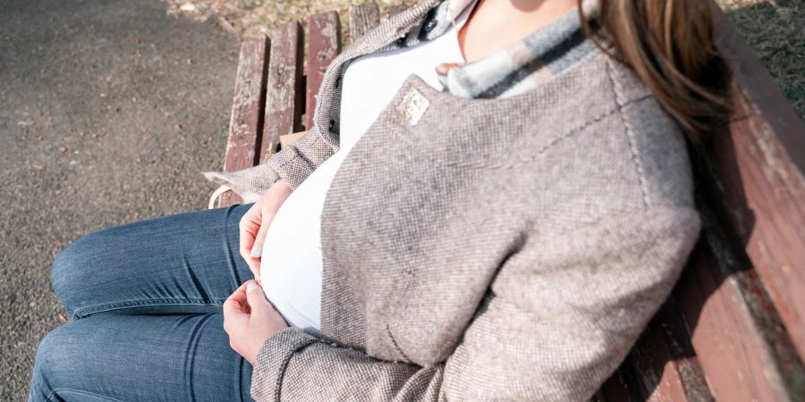 Schwangere Frau sitzt in der Sonne