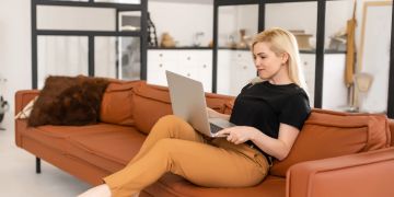 Frau mit Laptop auf Sofa