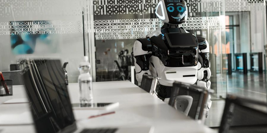 Ein humanoider Computer steht in einem Konferenzraum und lächelt