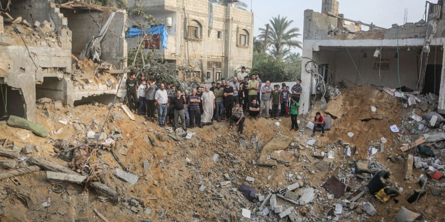 Palästinenser stehen in Chan Junis im Gazastreifen um einen Krater herum, der durch einen israelischen Angriff verursacht wurde.