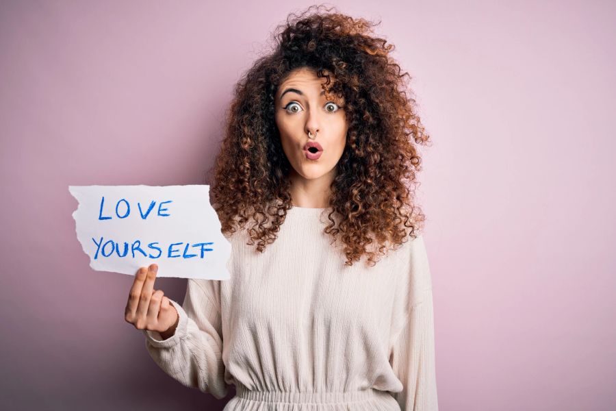 frau hält schild mit love yourself in der hand