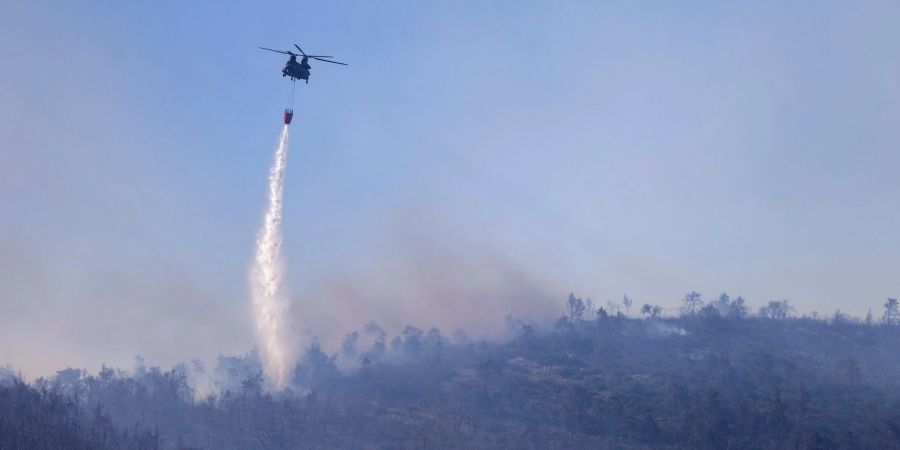 Ein Hubschrauber wirft Wasser auf einen Waldbrand im Norden Athens ab.