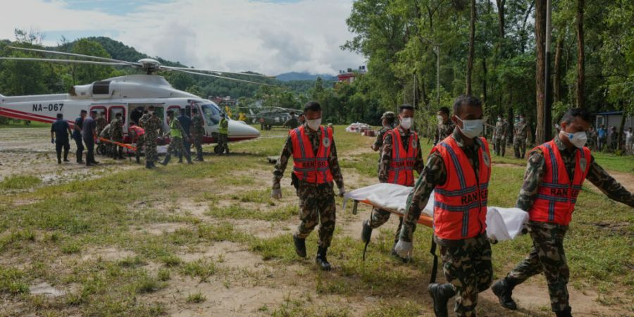 Soldaten der nepalesischen Armee tragen auf einem Hubschrauberlandeplatz in einem Armeelager im Distrikt Nuwakot in Nepal ein Opfer der Sturzfluten in einem Leichensack. Foto: Rajesh Ku...
