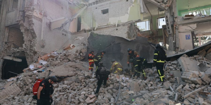 Rettungskräfte räumen die Trümmer weg, nachdem eine russische Bombe das Zentrum von Saporischschja in der Ukraine getroffen hatte. Foto: Kateryna Klochko/AP/dpa