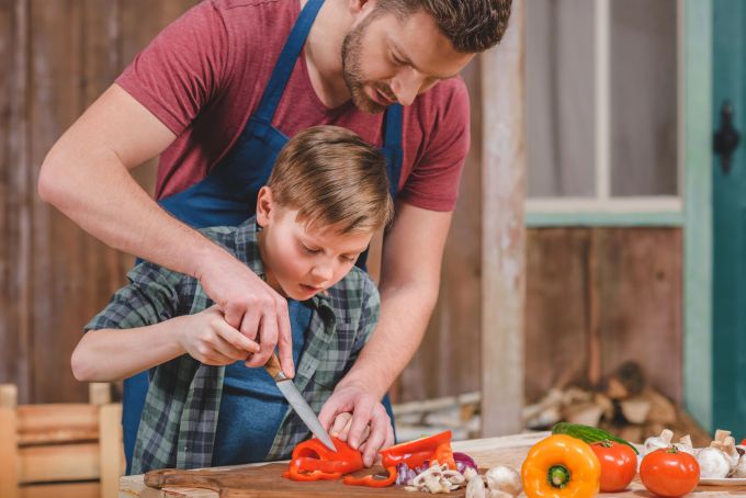 Kinder bekommen ein besseres Gespür für eine gesunde und ausgewogene Ernährung, wenn sie bei der Zubereitung miteinbezogen werden. kind kochen zusammen familienessen stressfrei