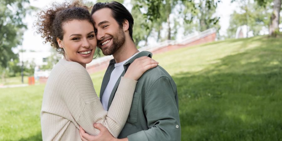 mann und frau lächeln, schmiegen sich aneinander, park