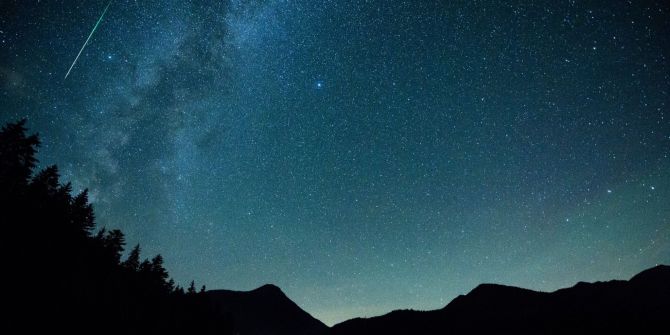 Eine Sternschnuppe leuchtet am Himmel über dem Walchense (Bayern)