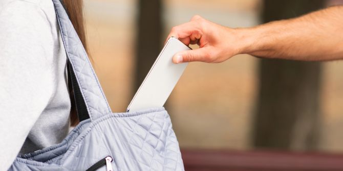 Handydiebstahl, Person klaut Smartphone aus Tasche