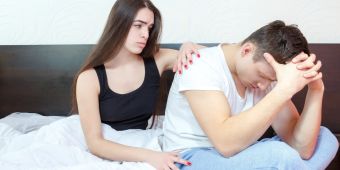 Frau tröstet depressiven mann im Bett.