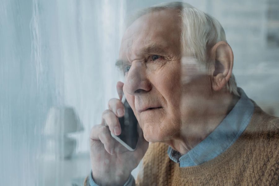 älterer mann am apparat, am fenster stehend