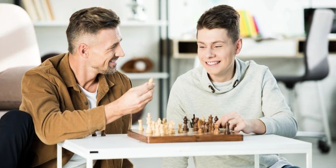 Sein Sie sehr aufmerksam mit Ihrem Teenager und finden Sie ein gemeinsames Hobby. Vater und Sohn spielen Schach
