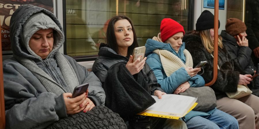 ARCHIV - Fahrgäste schauen auf ihre Smartphones, während sie in der Moskauer U-Bahn fahren. Foto: Alexander Zemlianichenko/AP/dpa/Archivbild