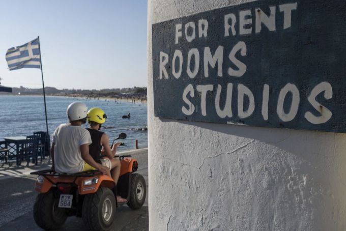 Touristen fahren ihren Miet-Quad an einer Fahne von Griechenland vorbei am Strand. Naxos Greichenland Quad