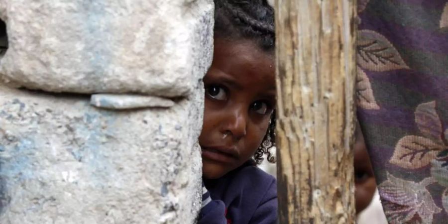 Ein kleines Mädchen hinter einer Mauer in einem Slum eines Kriegsgebiets von Sanaa. Wie schon in den beiden Jahren zuvor, ist Jemen das Land mit dem höchsten Risiko einer humanitären Notlage im Jahr 2021. Foto: Mohammed Mohammed/XinHua/dpa