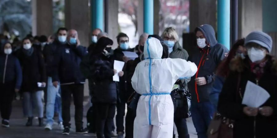 Menschen stehen vor einer Corona-Schnelltest-Einrichtung in Bozen (Südtirol) Schlange. Foto: Antonio Calanni/AP/dpa