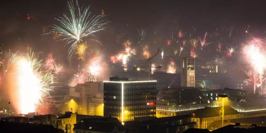 Feuerwerk wird in den nächtlichen Himmel über der Stadt abgefeuert. Foto: Christoph Schmidt/dpa