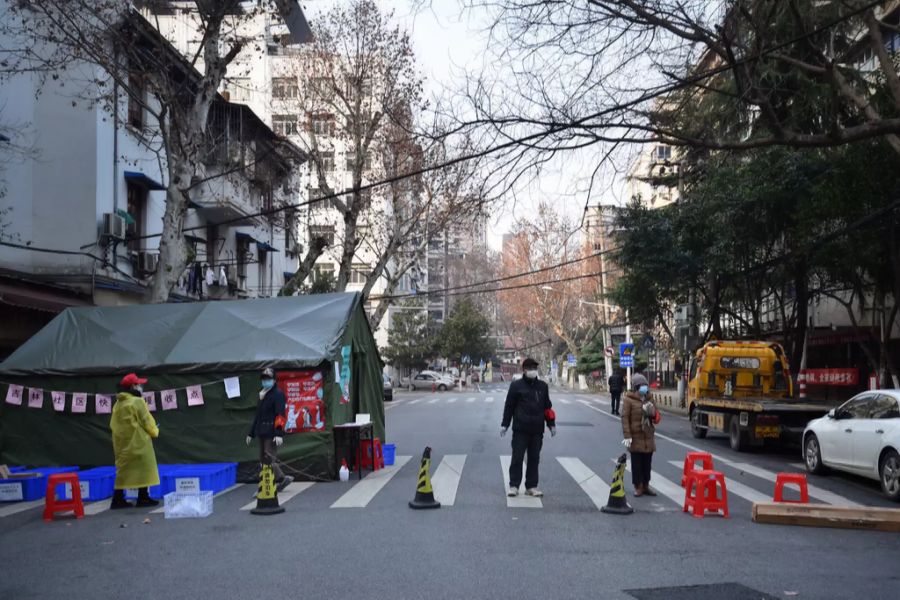 Regierungsangestellte und Freiwillige überwachen den Eingang eines abgeriegelten Wohngebiets Ende Februar in Wuhan.