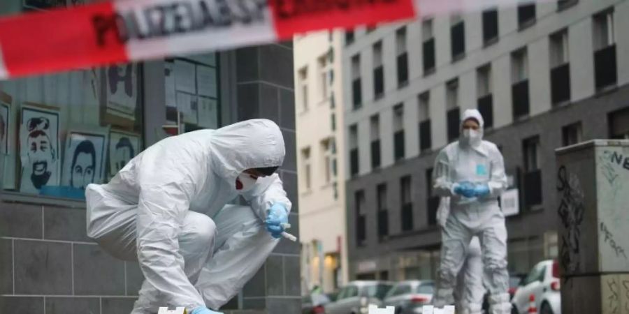 Beamte der Spurensicherung sichern Blutspuren auf dem Gehweg in der Frankfurter Niddastrasse. Foto: Frank Rumpenhorst/dpa