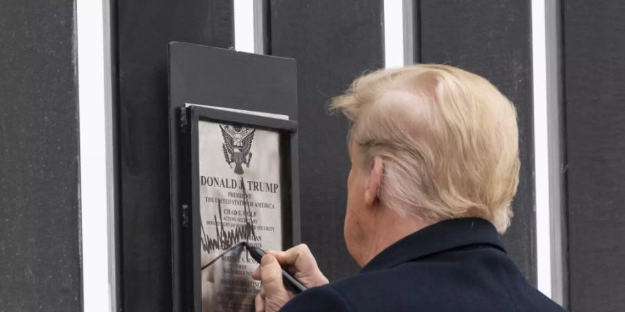 Donald Trump unterzeichnet eine Plakette an einem Abschnitt der US-Mexiko-Grenzmauer. Foto: Alex Brandon/AP/dpa